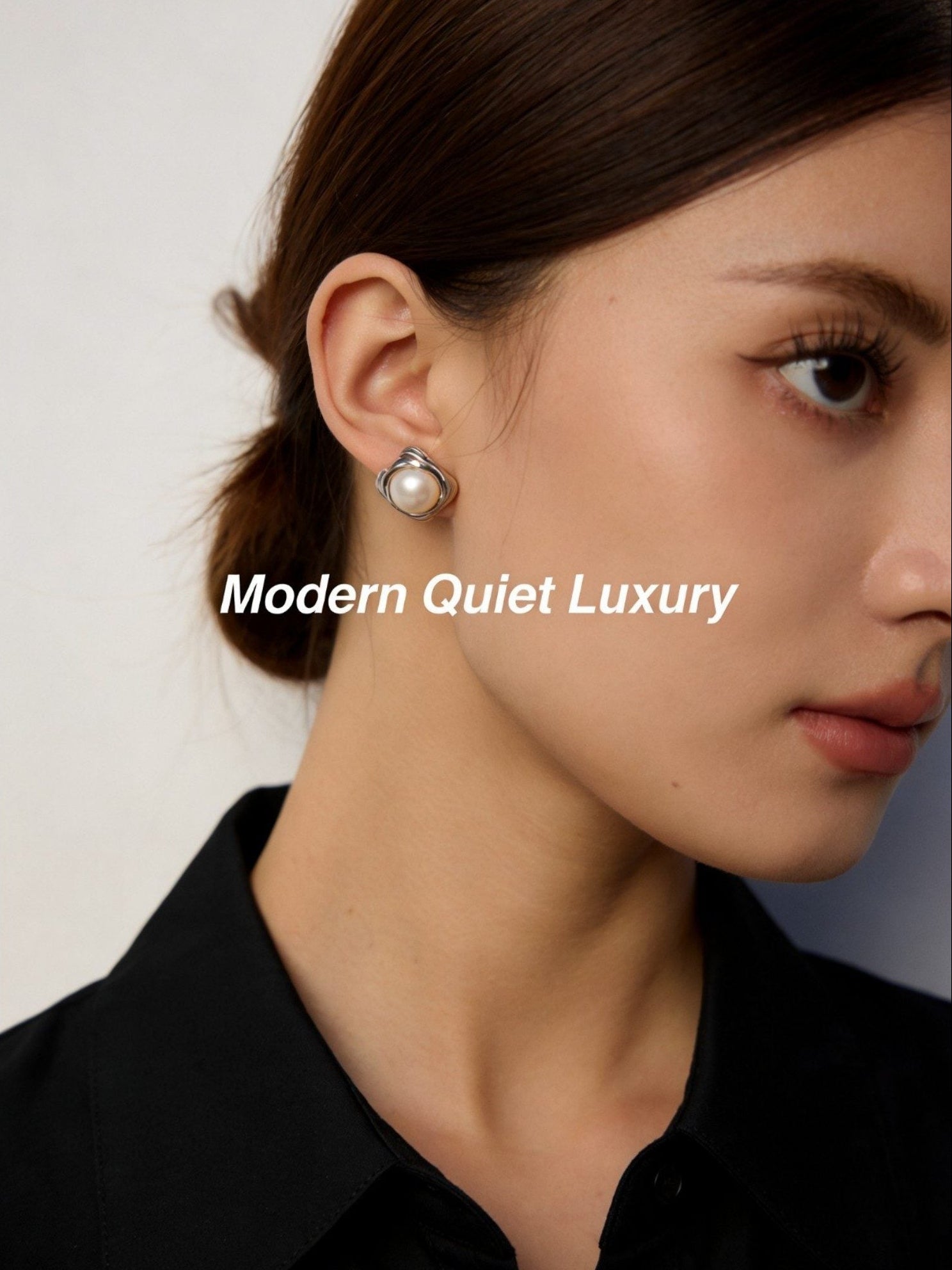 Close-up shot of an artisanal hammered silver pearl stud earring held by a hand to show scale and metallic texture.